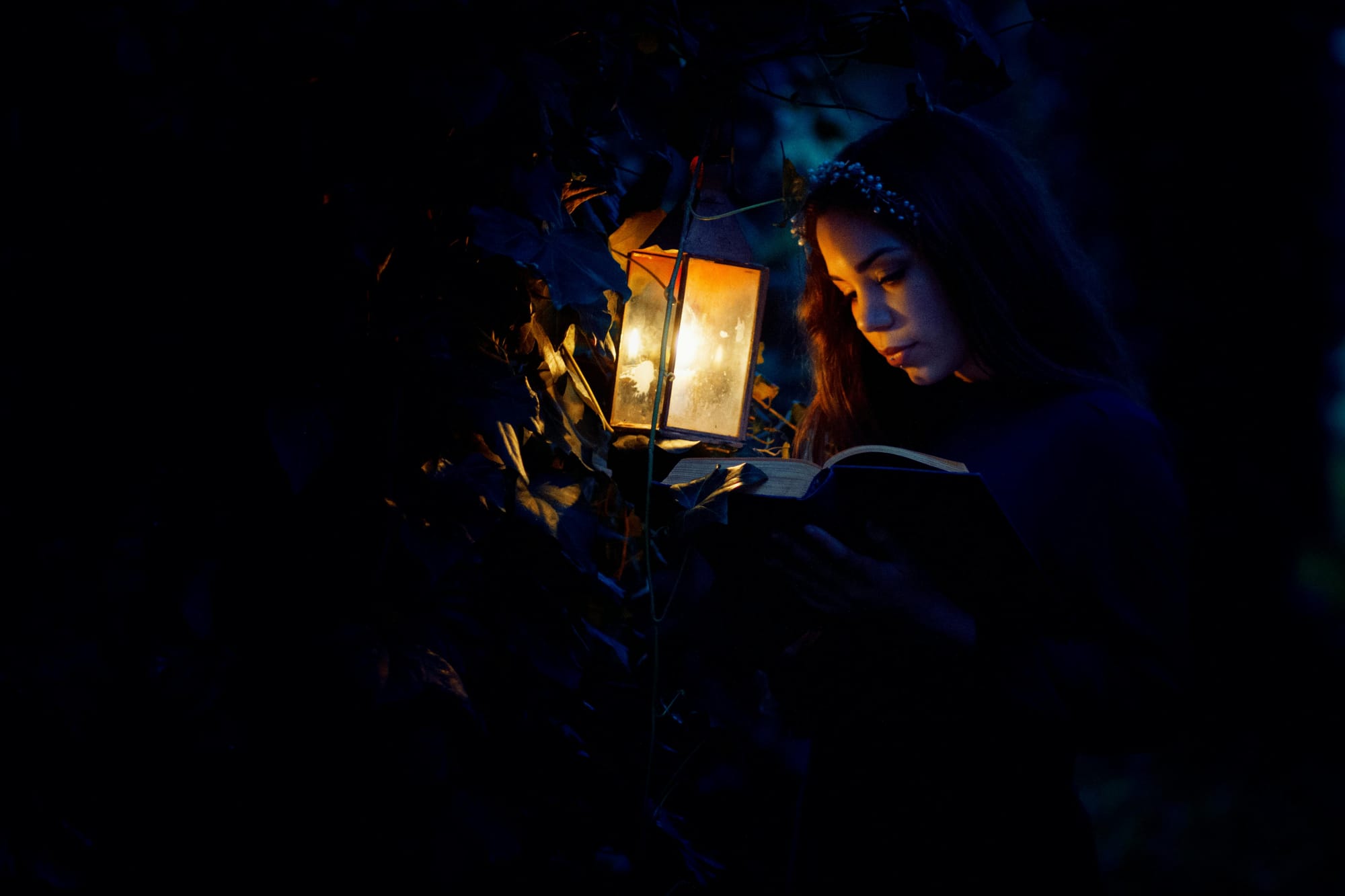 A woman reading a book by a kerosene lamp