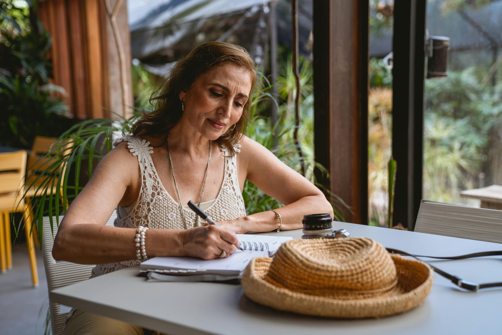 middle-aged woman in travel clothes writing in notebook