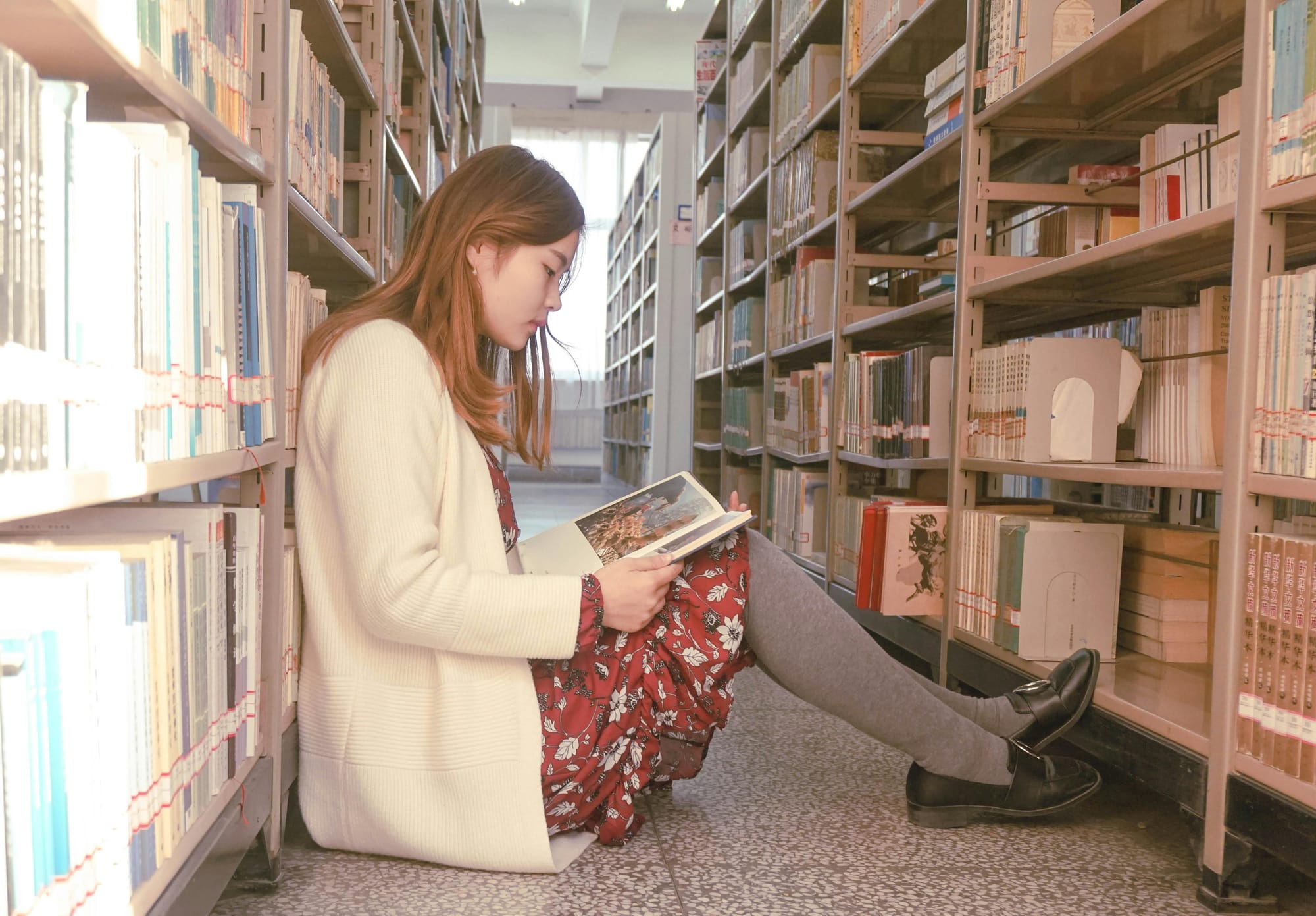 woman sitting on the floor in a library reading a book