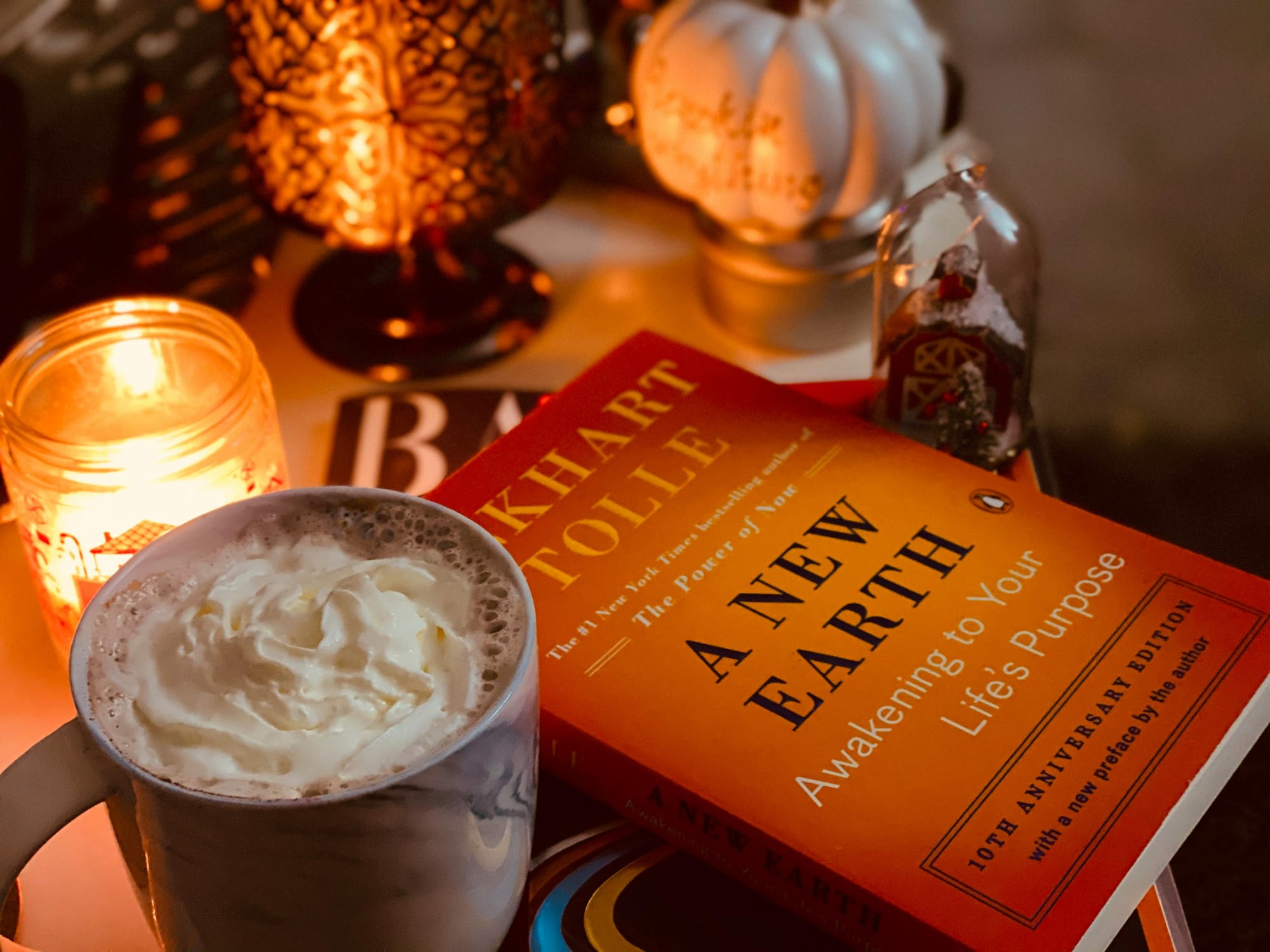 bedside table with a book by Eckhart Tolle, coffee and a candle