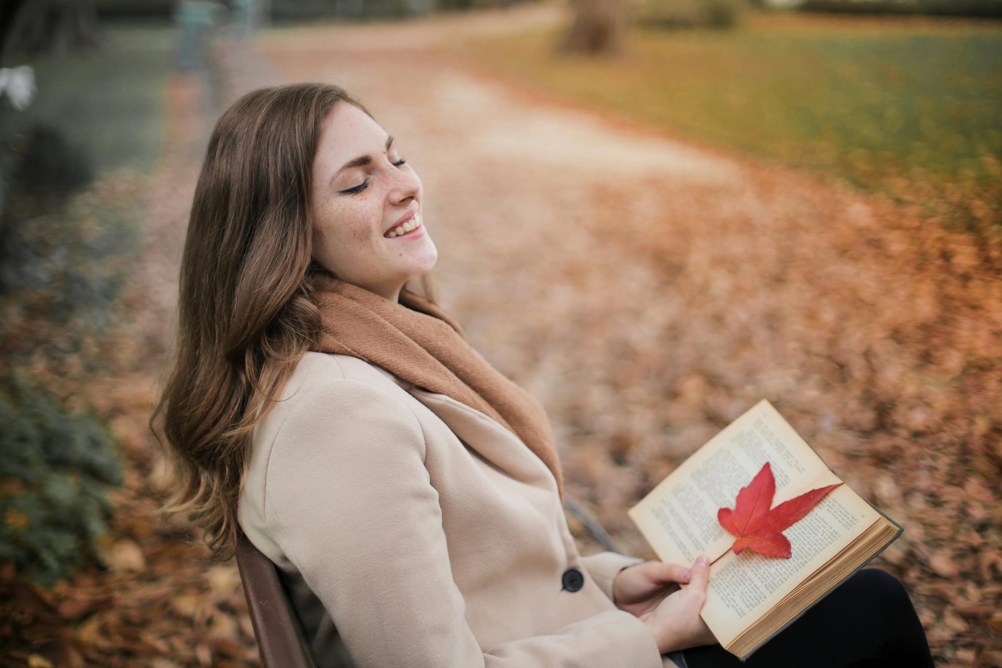 cheerful woman sitting in the park with a book