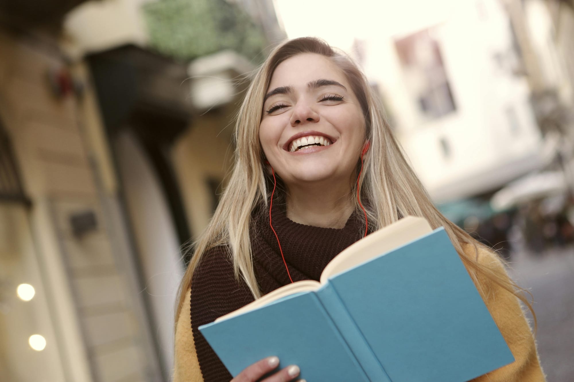 smiling woman with headphones and a book in her hand