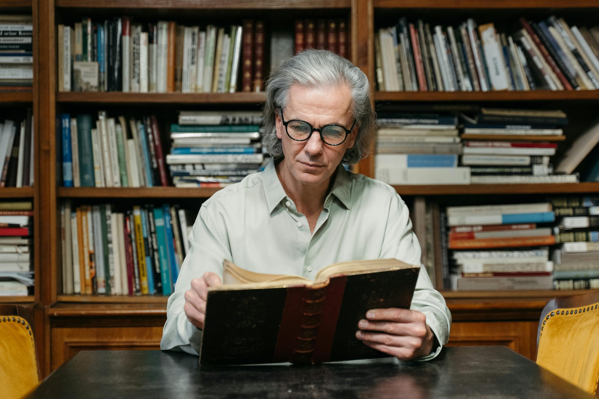 an elderly man sitting and reading an old book