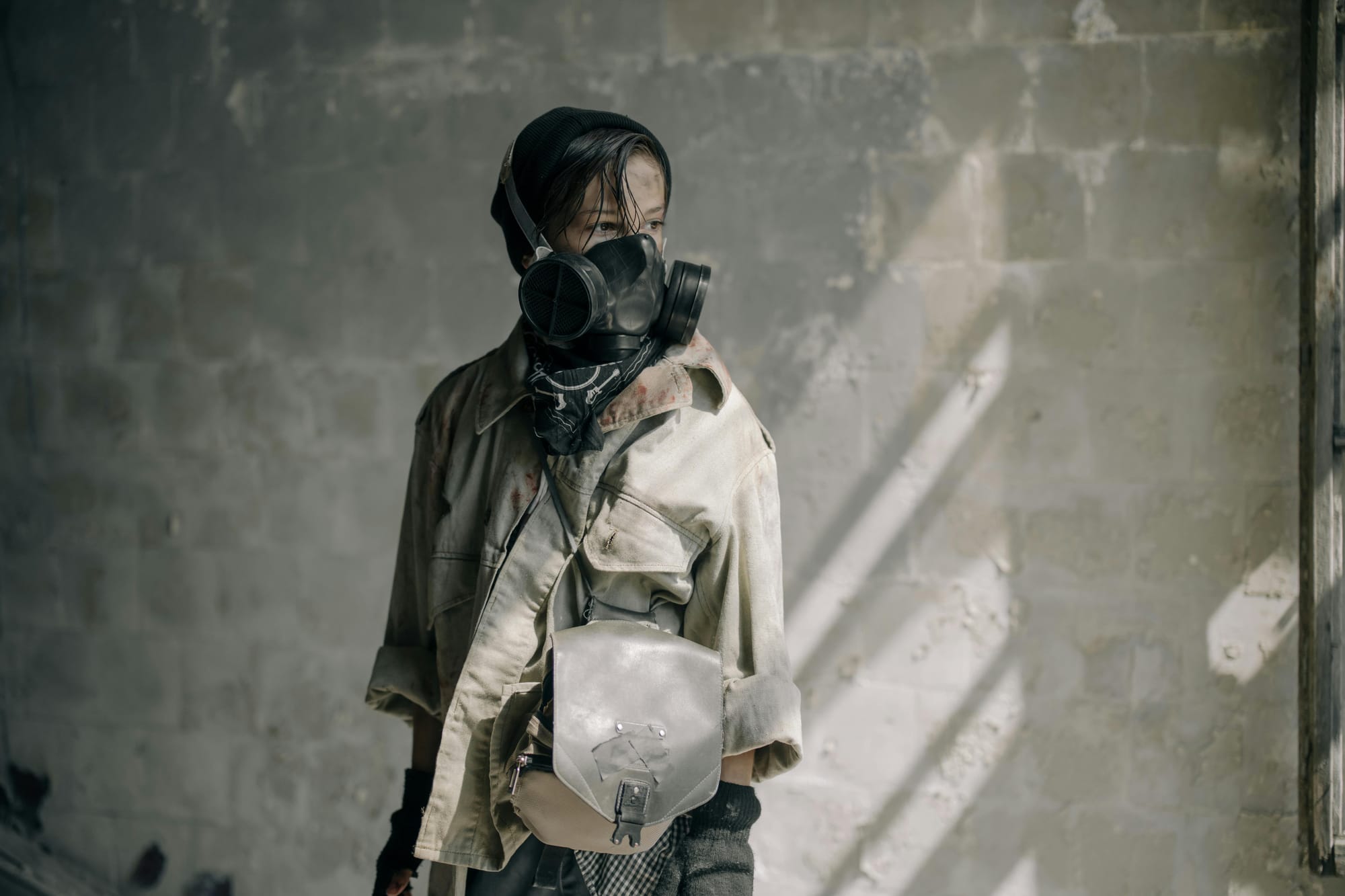 a boy in a large gas mask and leather jacket looking into the distance