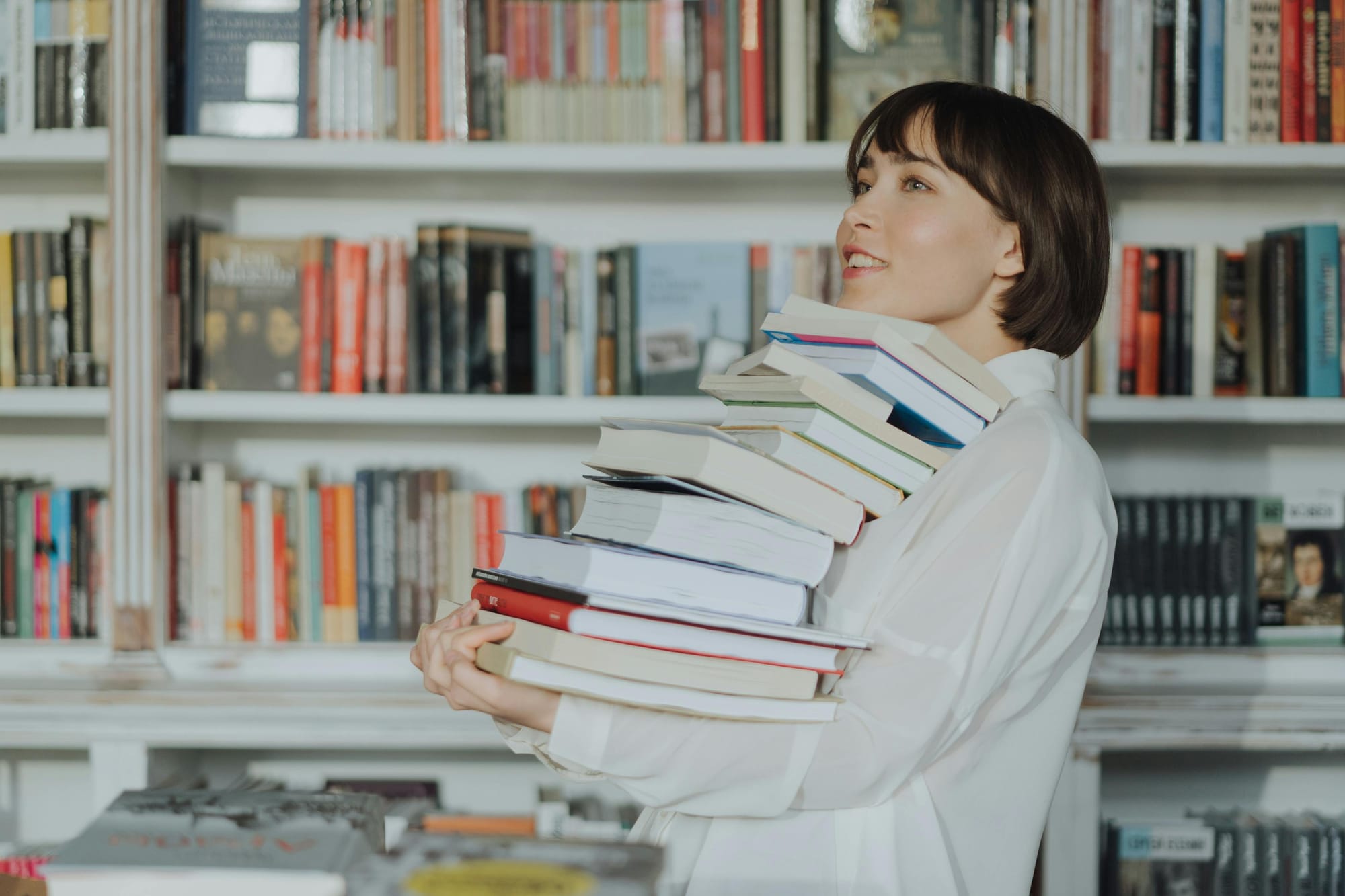 smiling woman holding a stack of books in the library